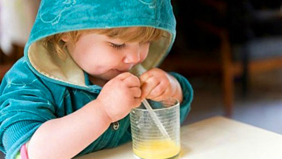 Ребенок пьет сок из яблок через трубочку